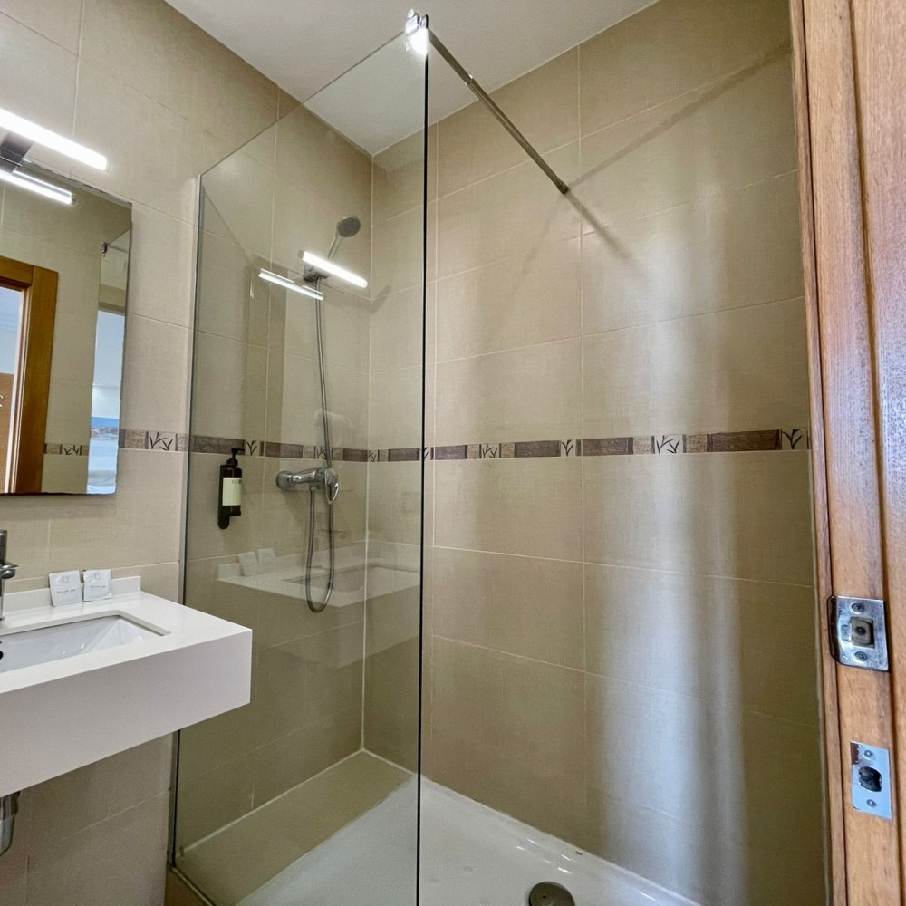 A bathroom with a walk in shower , sink and mirror.