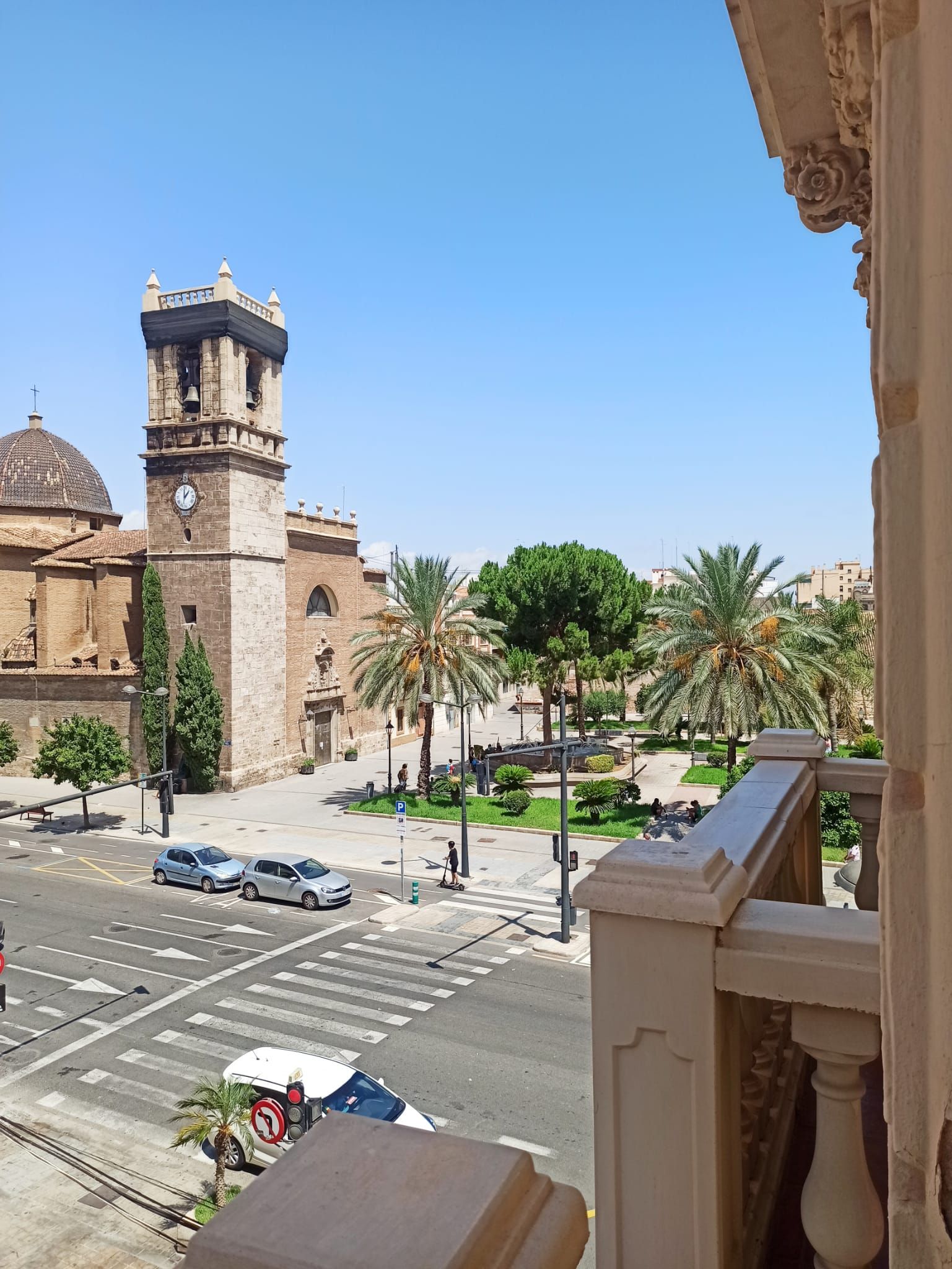 A view of a city from a balcony with a clock tower in the background
