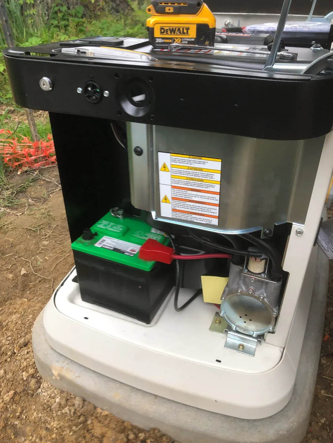 Open battery compartment with black and green batteries inside a white machine outdoors.
