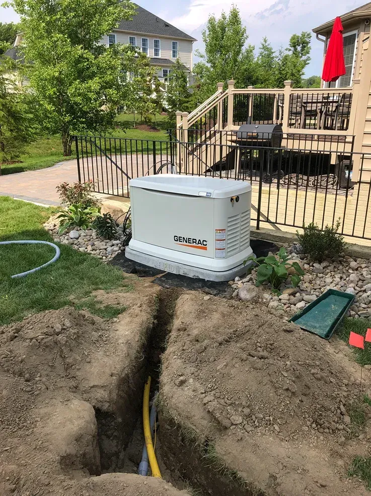 Backup generator installed beside deck with trench and exposed yellow utility line