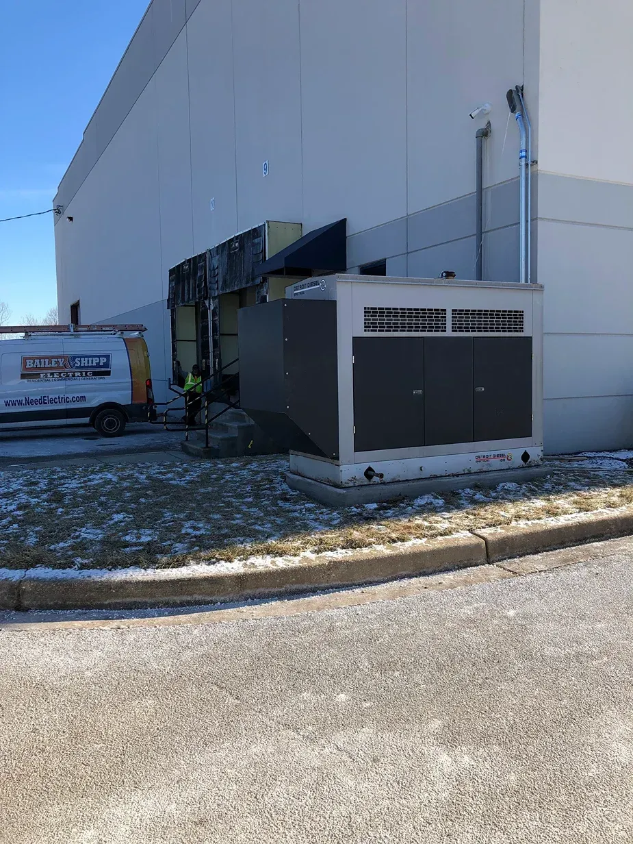 Industrial building exterior with HVAC units and a dumpster beside a snowy curb