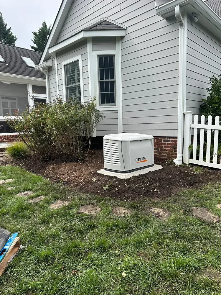 Outdoor home side yard with a white generator beside a gray house and white picket fence