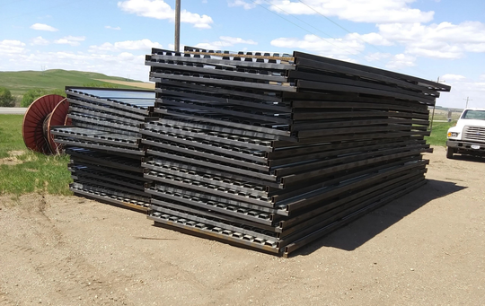 A truck is parked next to a pile of metal sheets