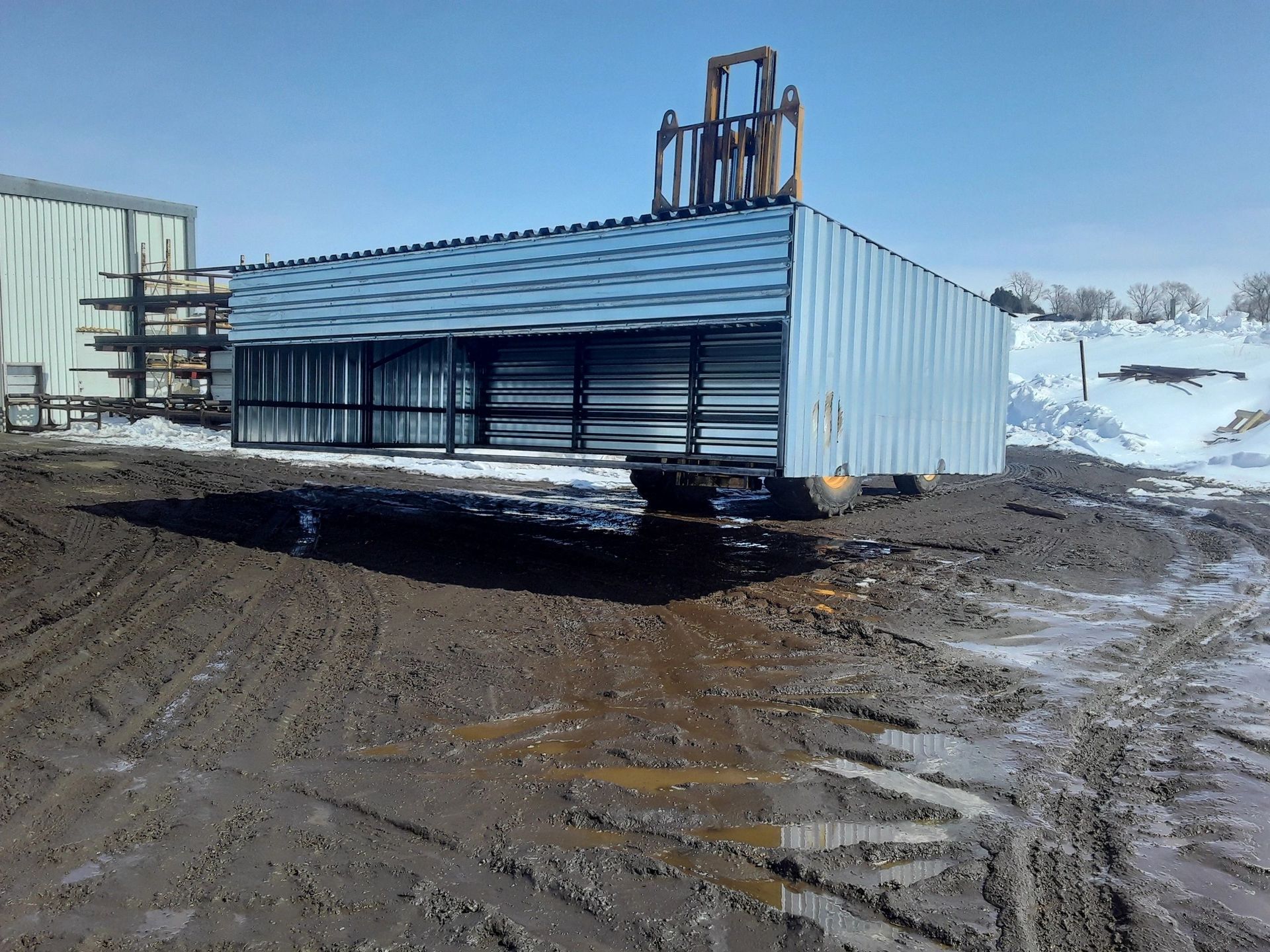 A trailer is parked in a muddy field in front of a building