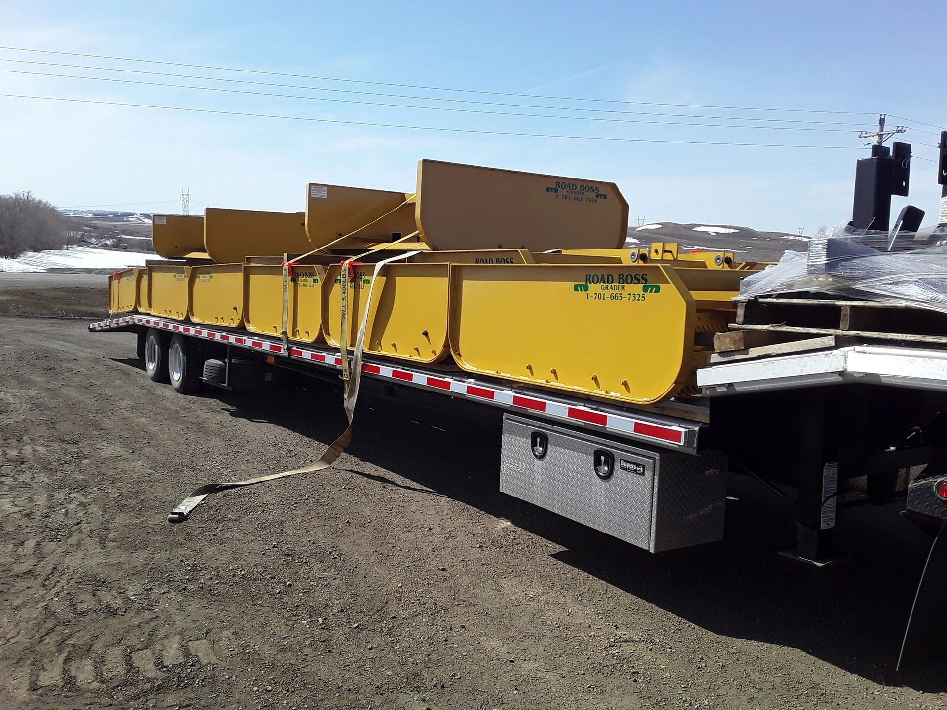 A large yellow trailer is sitting on a dirt road.