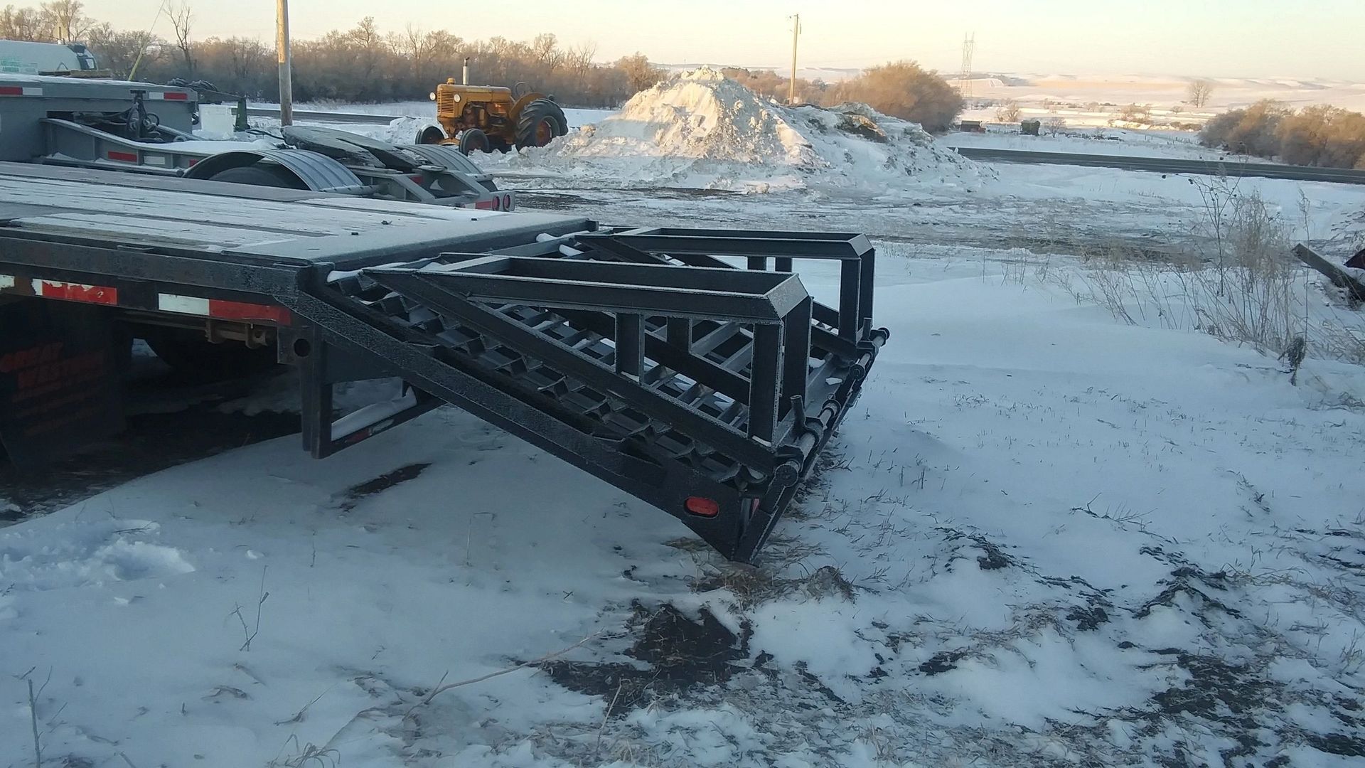 A trailer is sitting on top of a snow covered field.