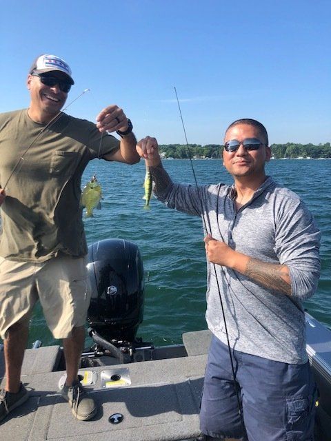Two men are fishing on a boat and one is holding a fish