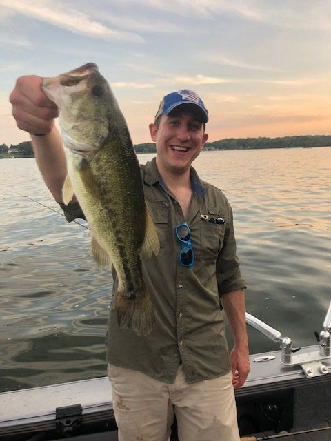 A man is holding a large fish in his hand on a boat.