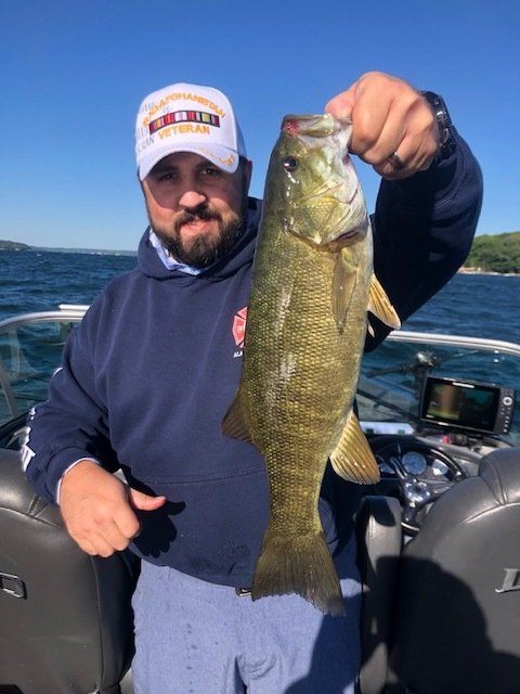 A man on a boat holding a large fish