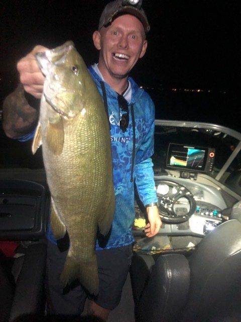 A man on a boat holding a large fish