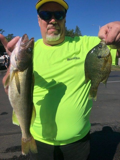 A man in a neon green shirt is holding two fish
