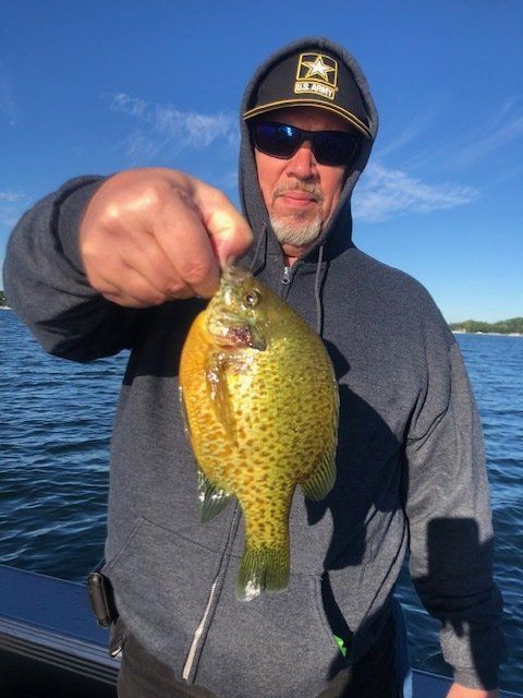 A man wearing a hat that says army is holding a fish