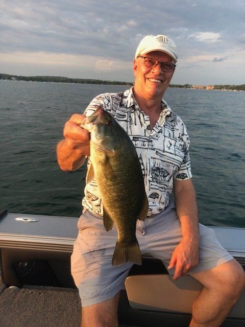 A man is sitting on a boat holding a large fish