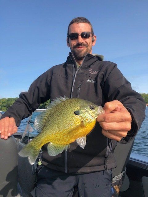 A man in a black jacket is holding a yellow fish