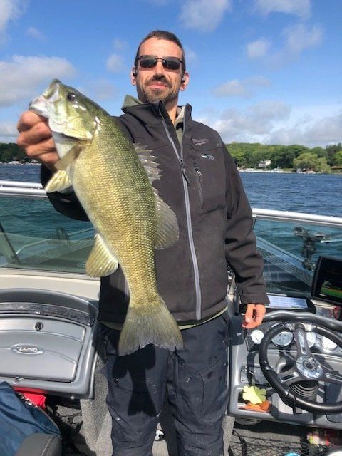 A man is holding a large fish in front of a boat