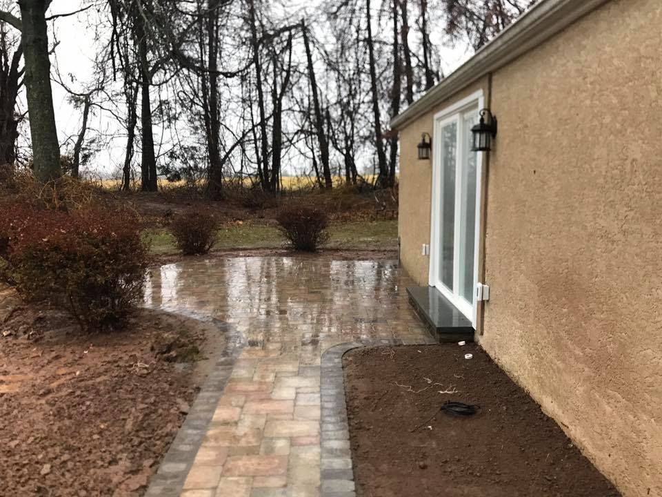A brick walkway leading to a house with a sliding glass door.