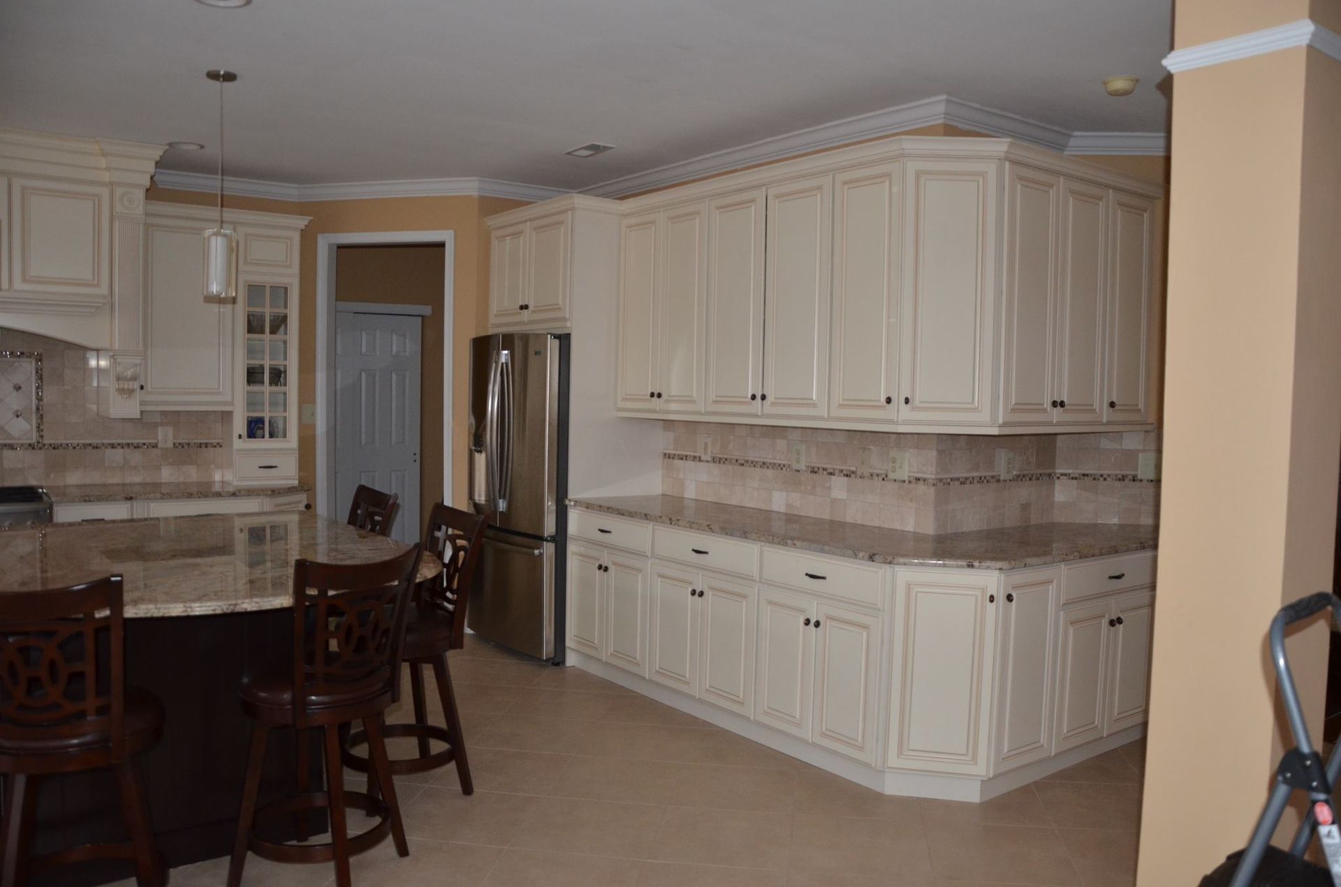 A kitchen with white cabinets , granite counter tops , stainless steel appliances and a large island.