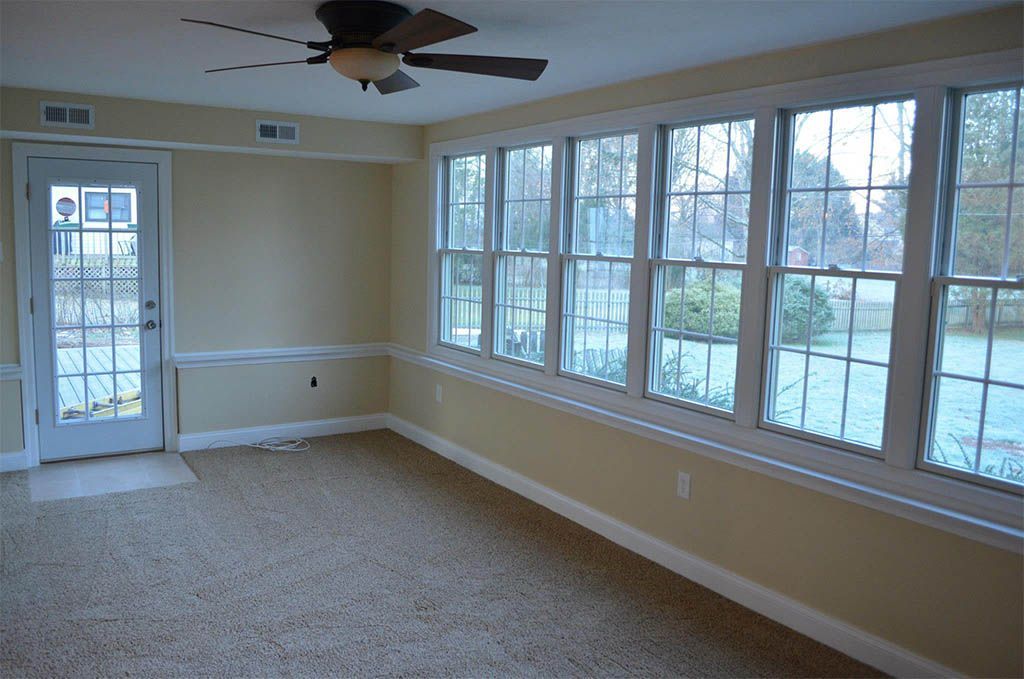 An empty room with a lot of windows and a ceiling fan