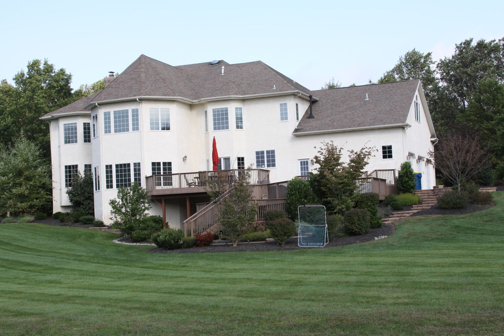 A large white house sits on top of a lush green hillside