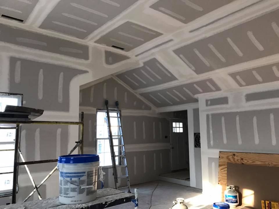 A bucket of paint sits on a scaffolding in a room under construction