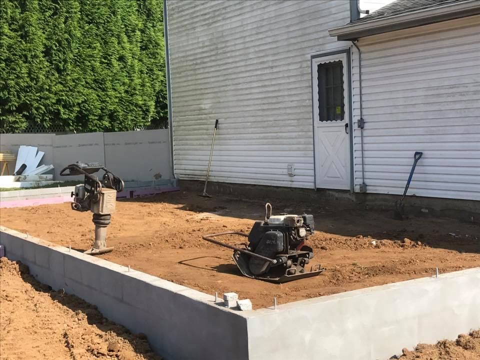 A machine is sitting in the dirt in front of a house.