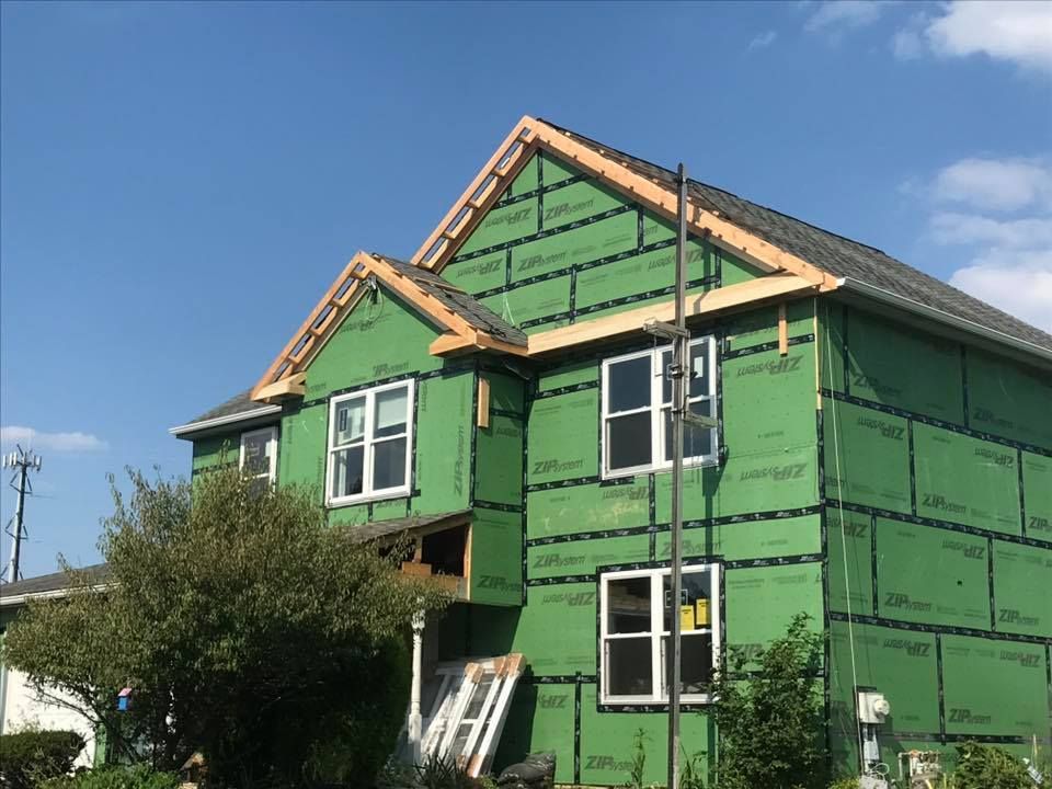 A house is being built with green siding and windows.