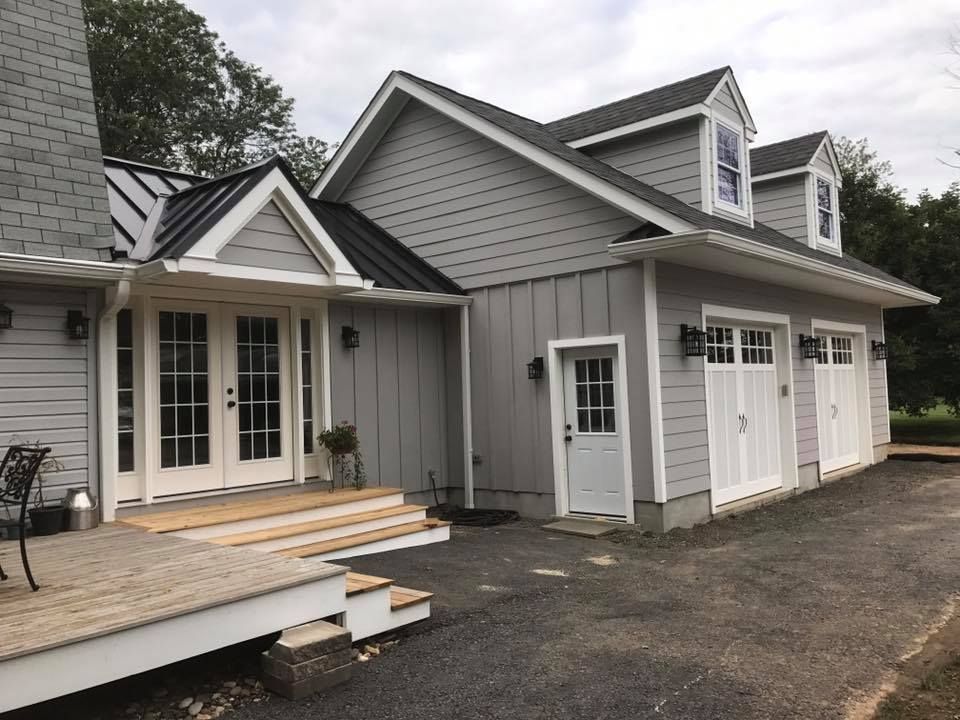 A large gray house with white doors and a black roof