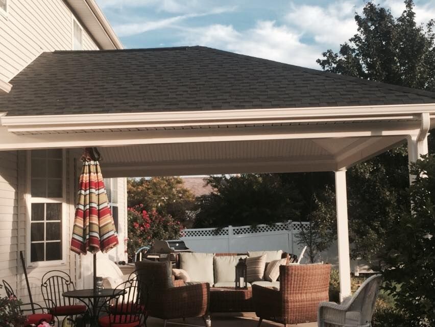 A porch with a couch and chairs under a roof