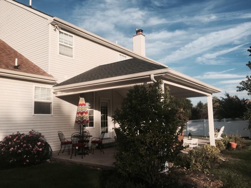 A white house with a covered porch with a table and chairs
