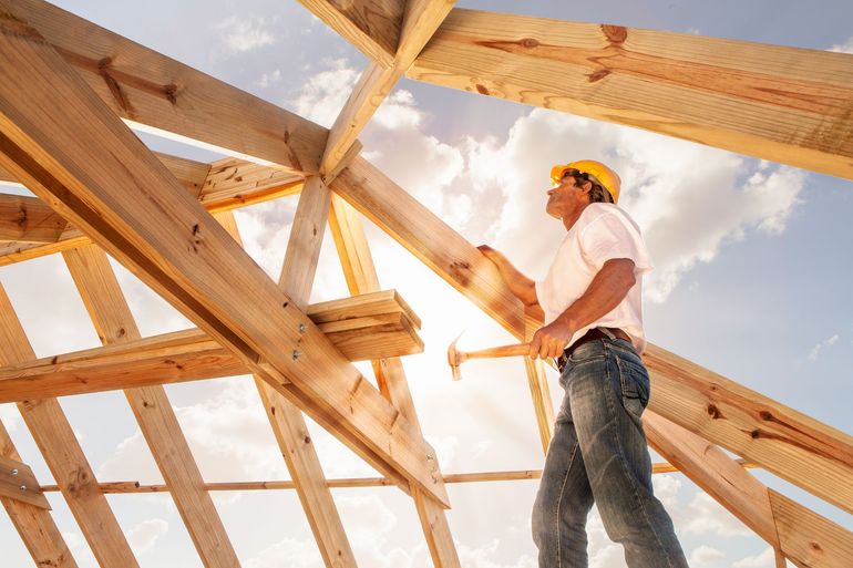 A man in a hard hat is standing on top of a wooden structure.