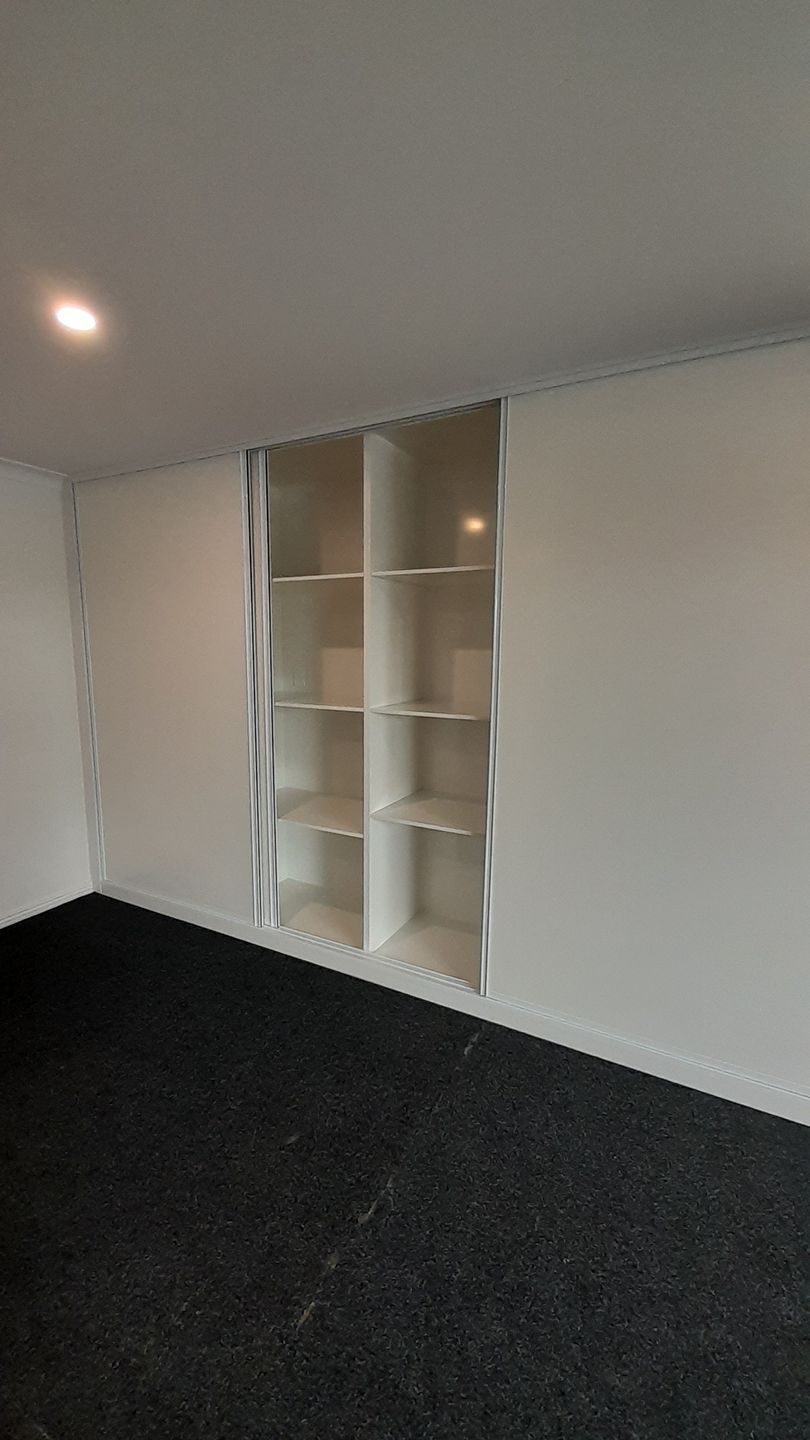 An empty room with a black carpet and white shelves.