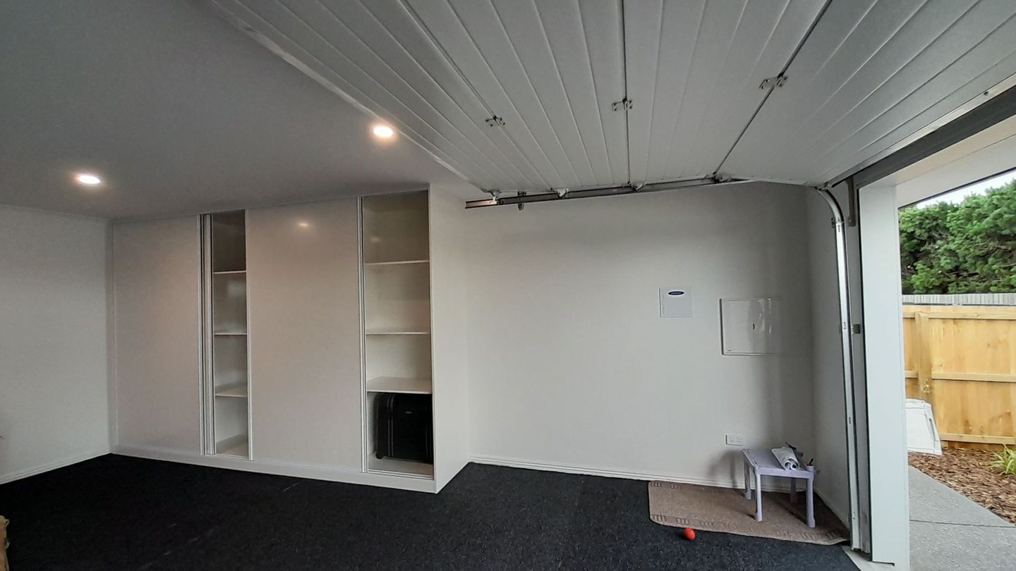 An empty garage with a garage door open and a table in the corner.