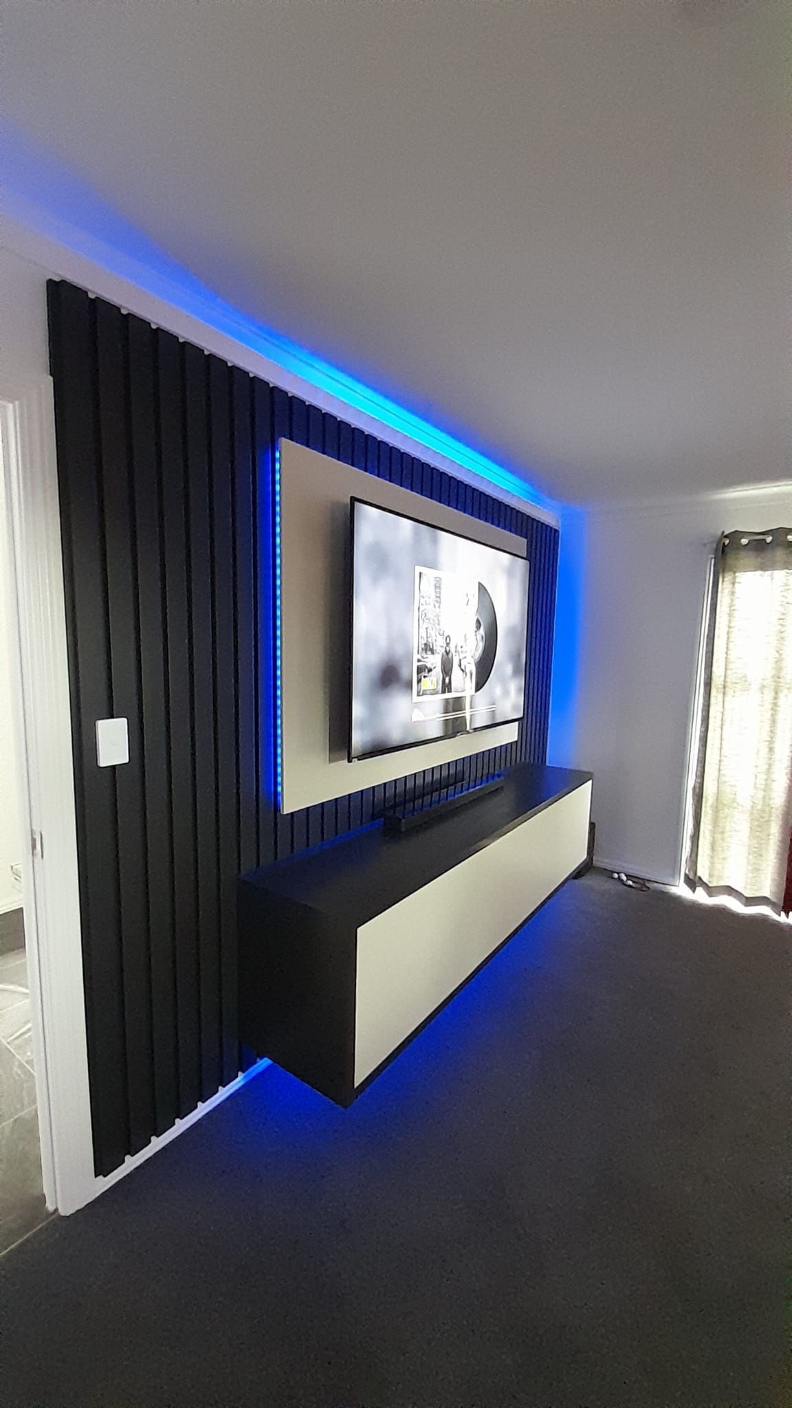 A living room with a flat screen tv mounted on the wall.