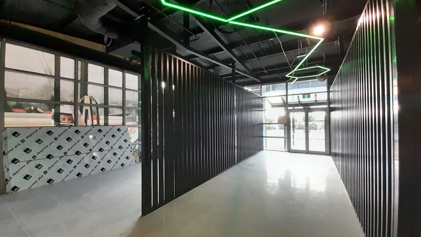 A long hallway with a green light hanging from the ceiling.