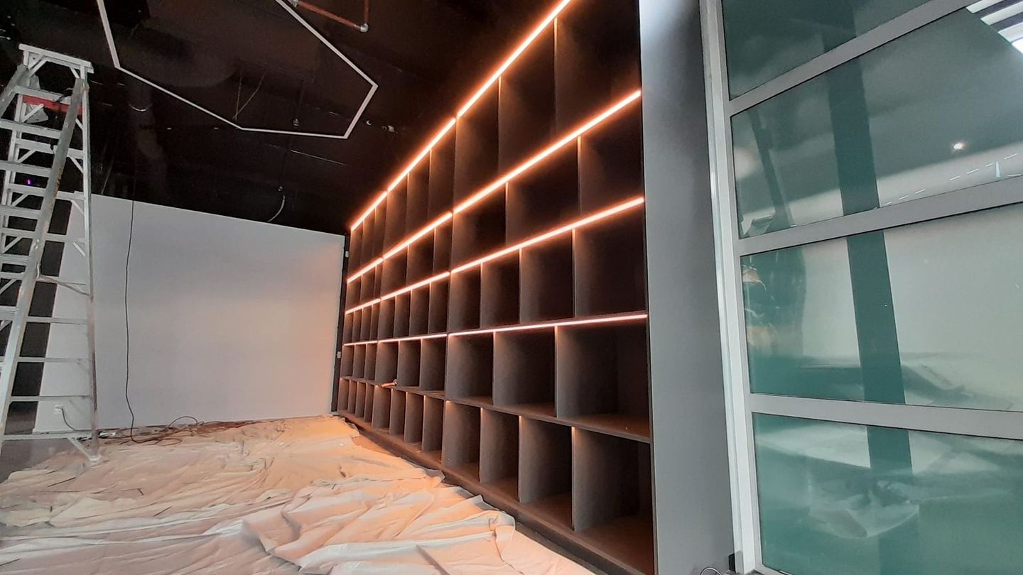 A room with a lot of shelves and lights on the wall.