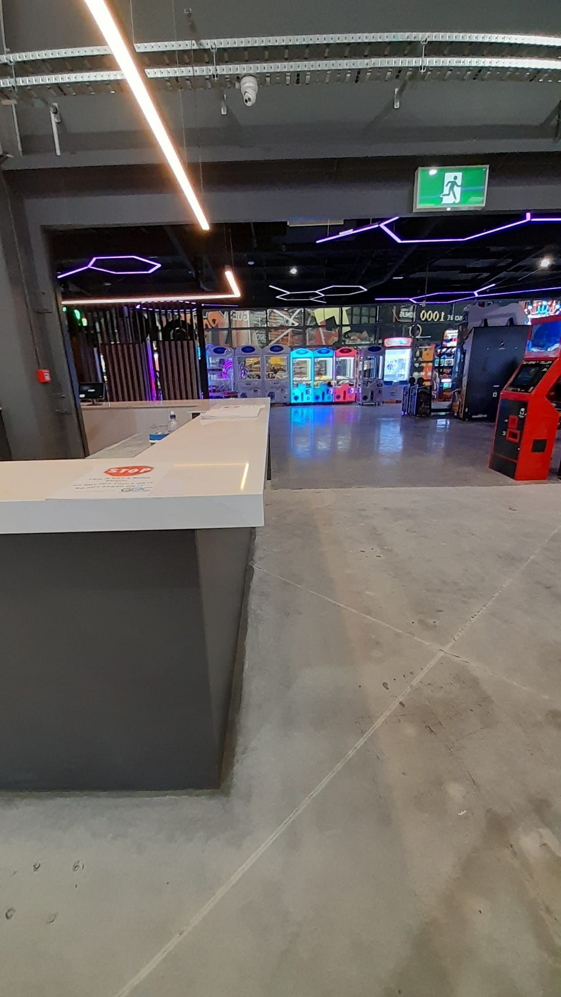 A large room with a lot of arcade games and a counter in the middle of it.