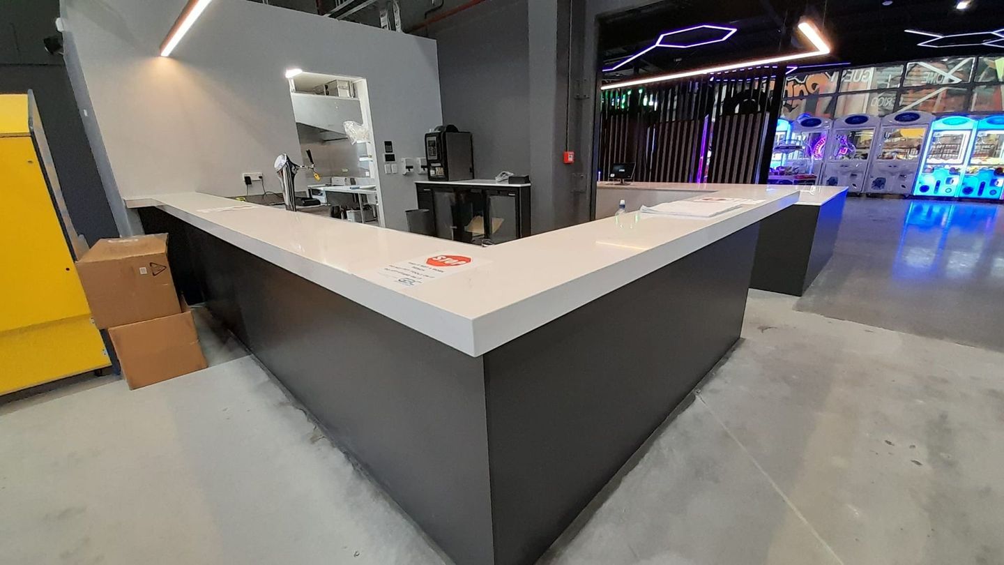 A large l shaped counter in a room with boxes on the floor.