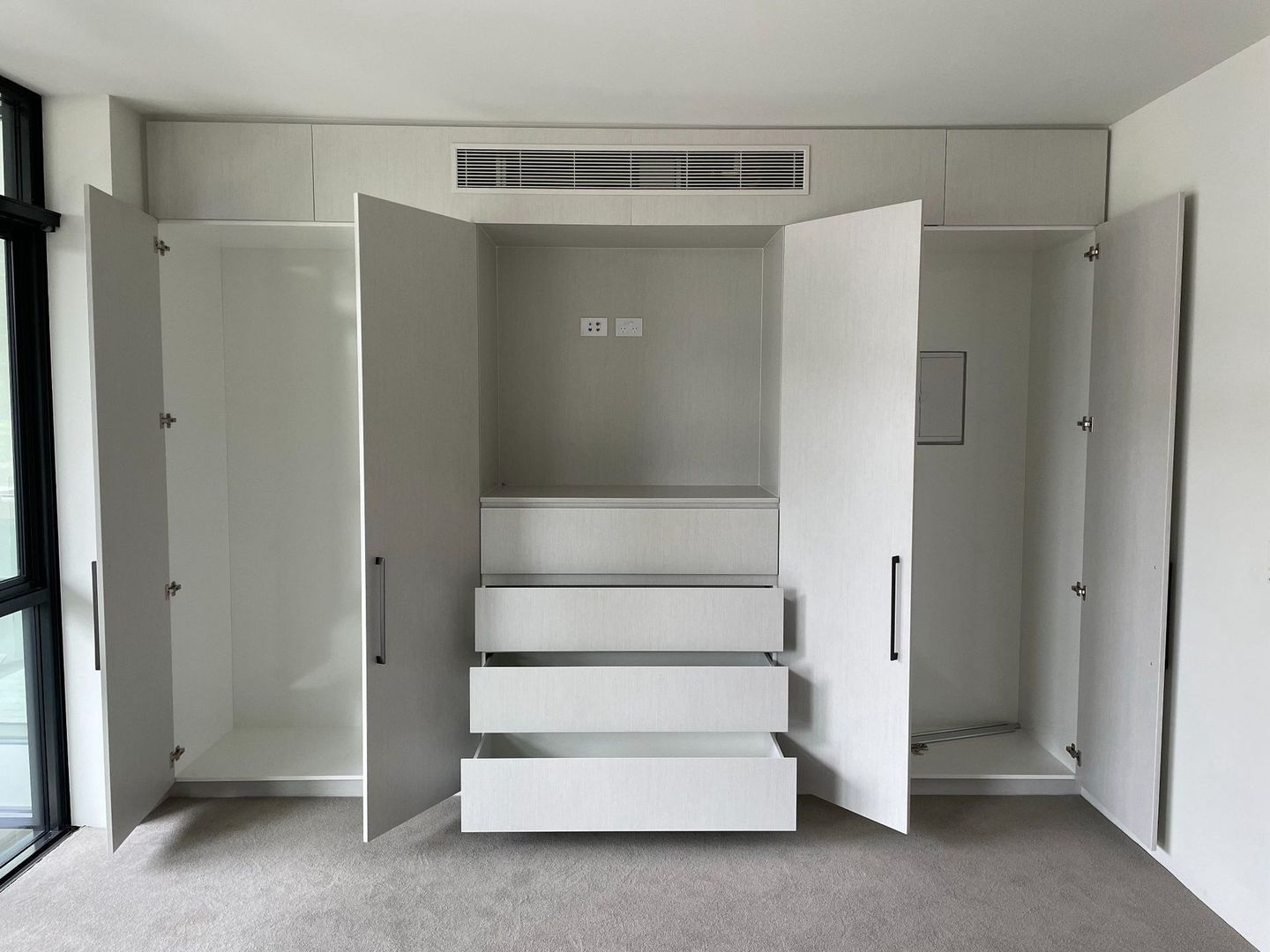 An empty wardrobe with the doors open and drawers visible