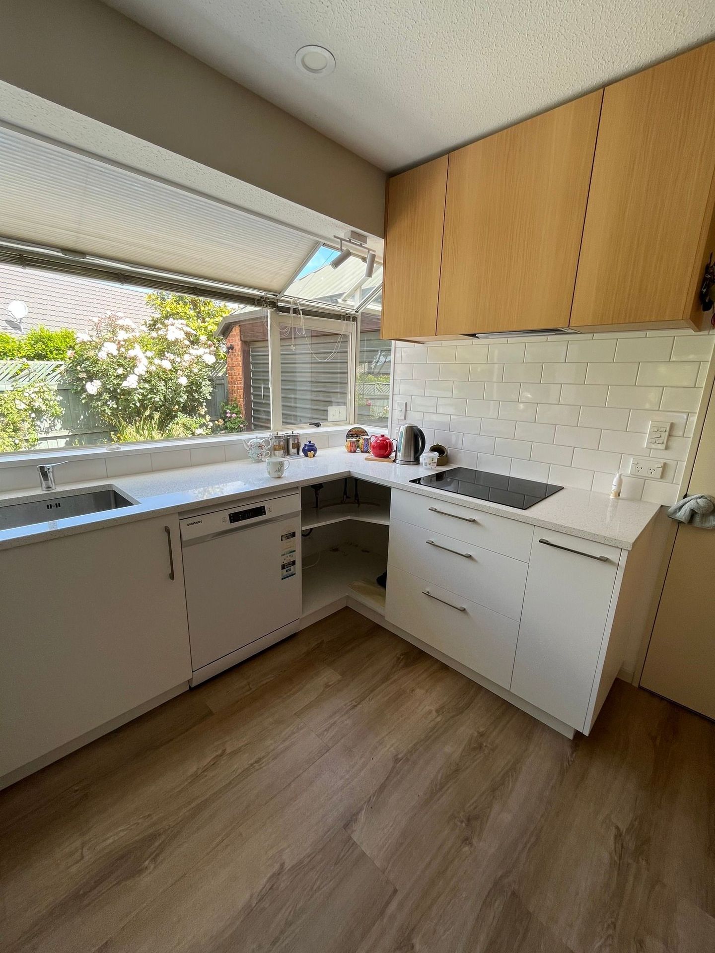 A kitchen with white cabinets , a stove , a sink and a window.