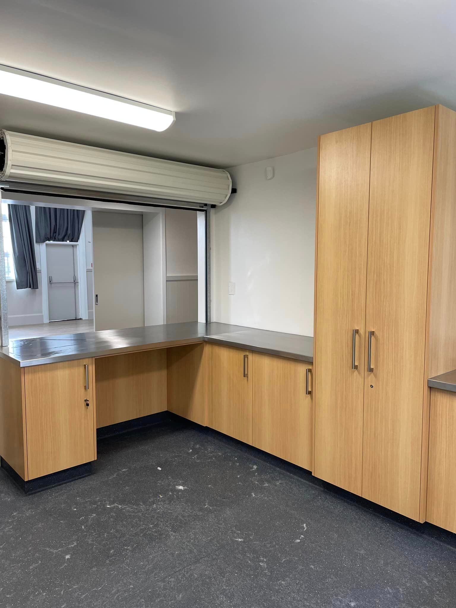 An empty room with wooden cabinets and a stainless steel counter top.