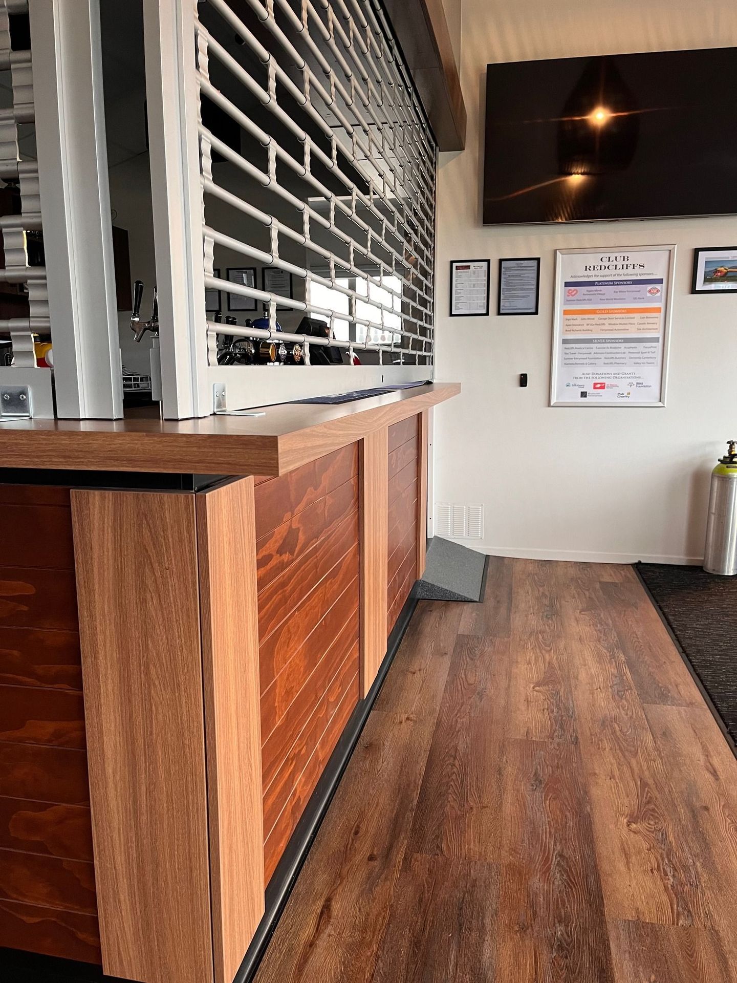 A long wooden counter in a room with a tv on the wall.