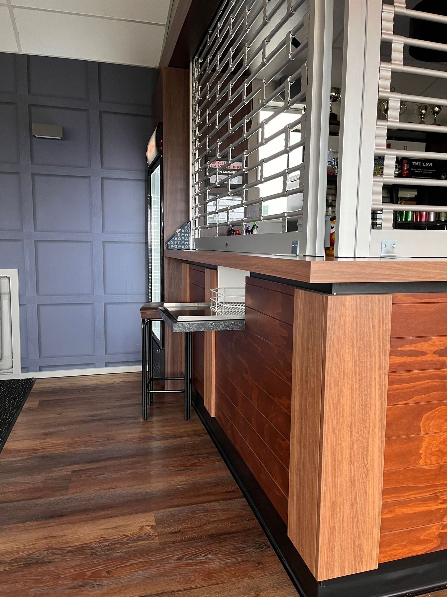 A wooden counter in a restaurant with a purple wall behind it.