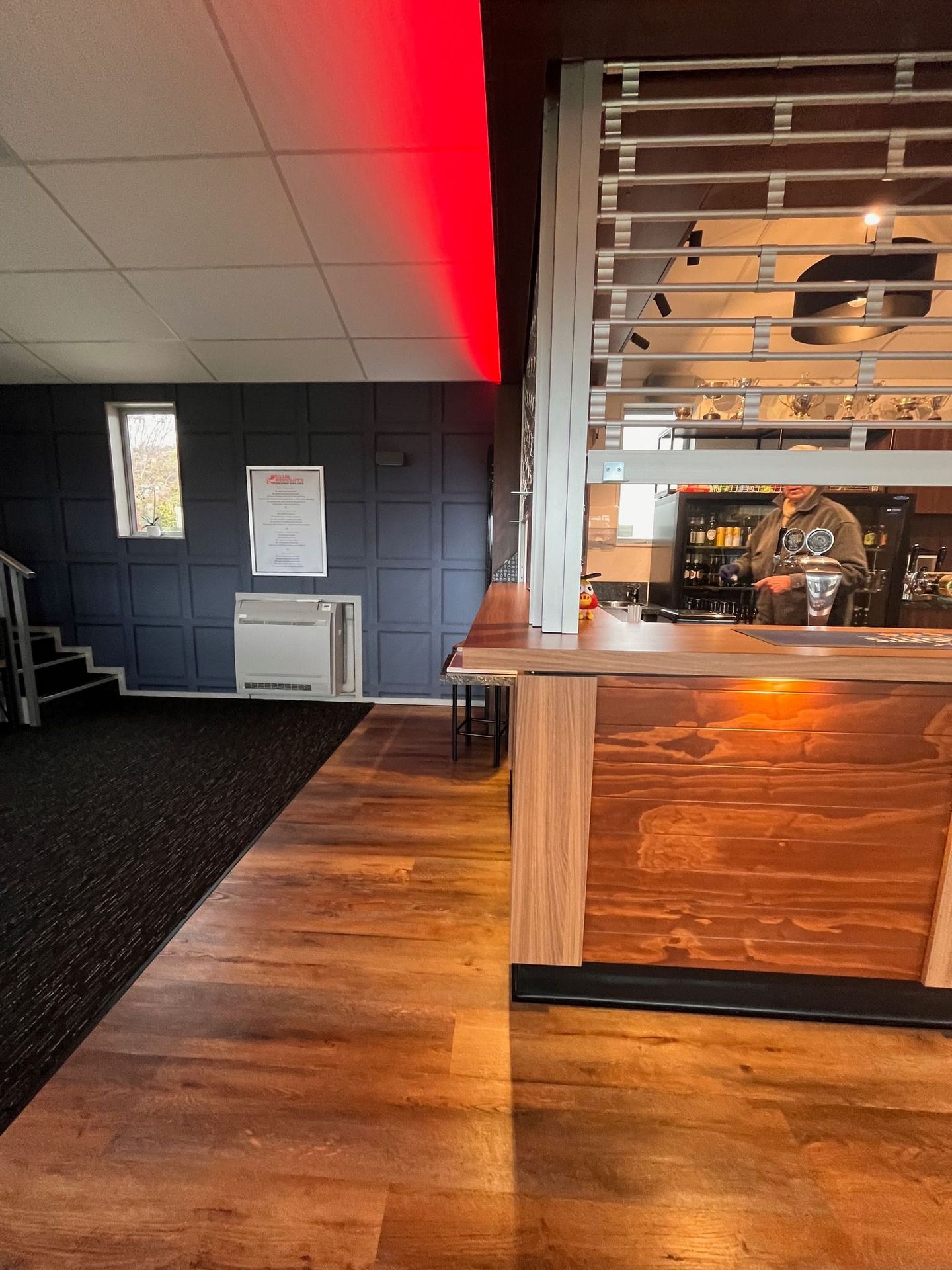 A man is standing behind a wooden counter in a restaurant.