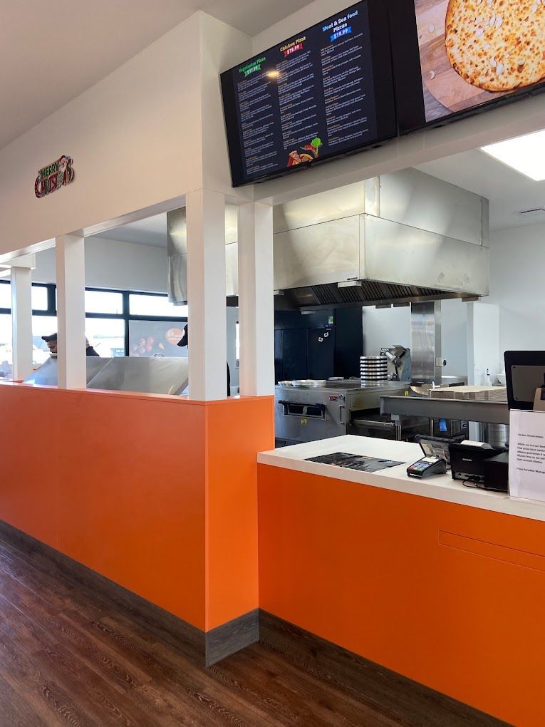 The inside of a restaurant with orange walls and a counter.