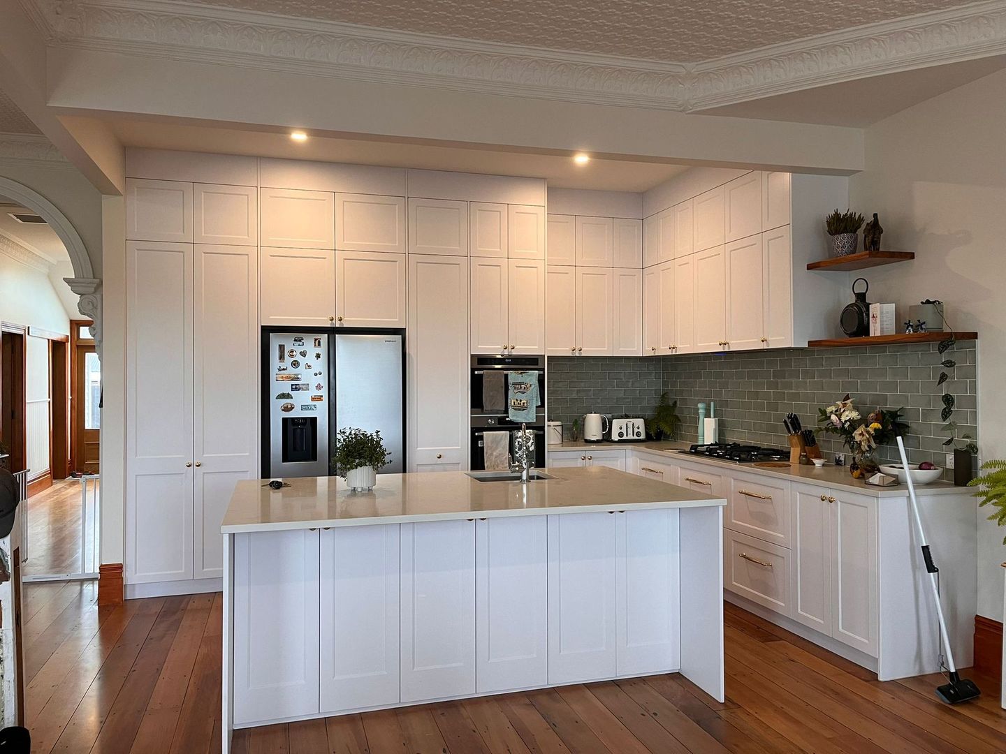 A kitchen with white cabinets and a large island in the middle.