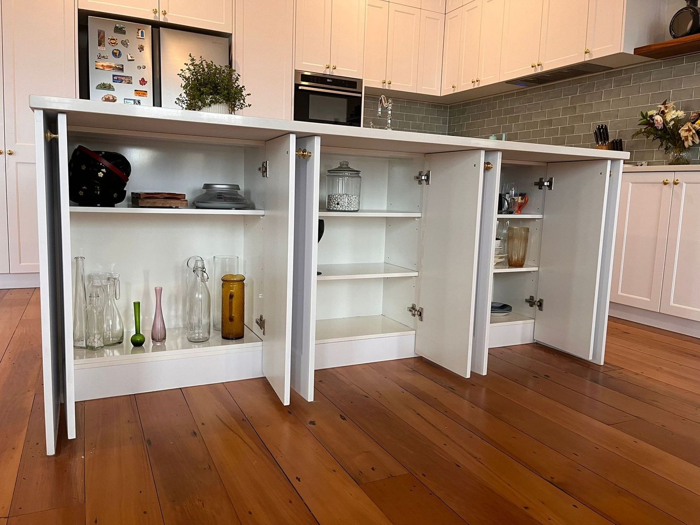 A kitchen with a lot of shelves and cabinets and a wooden floor.