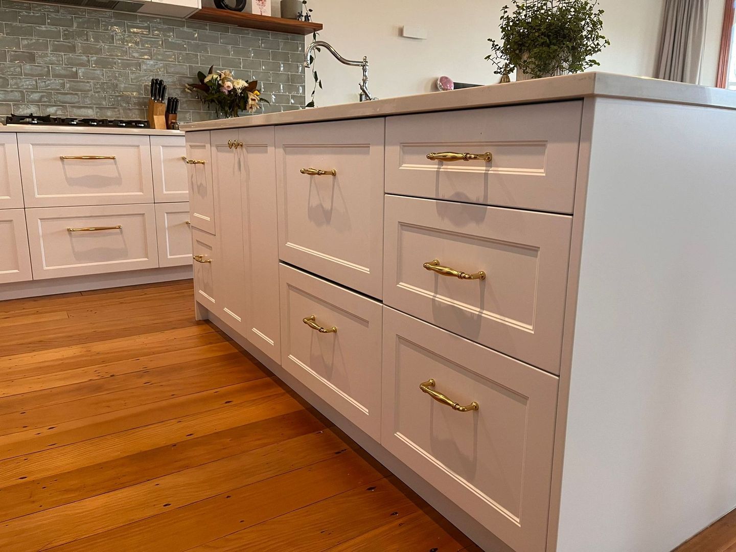 A kitchen with white cabinets and gold handles