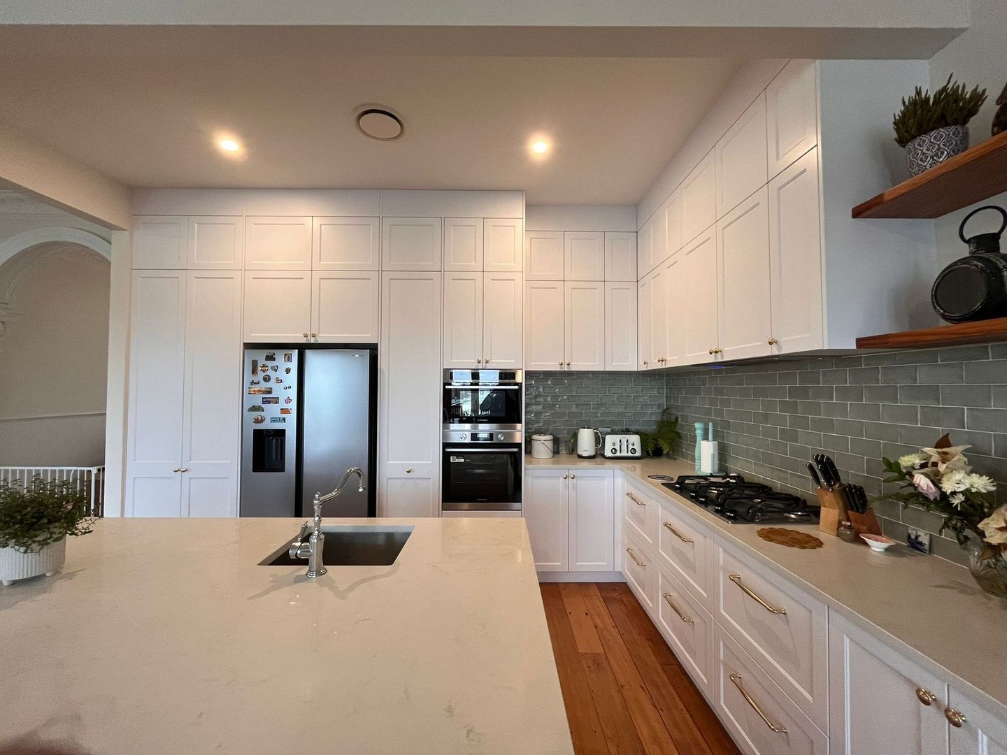 A kitchen with white cabinets , stainless steel appliances and a large island.