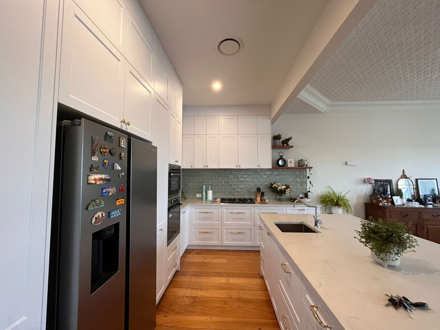 A kitchen with white cabinets and a black refrigerator.