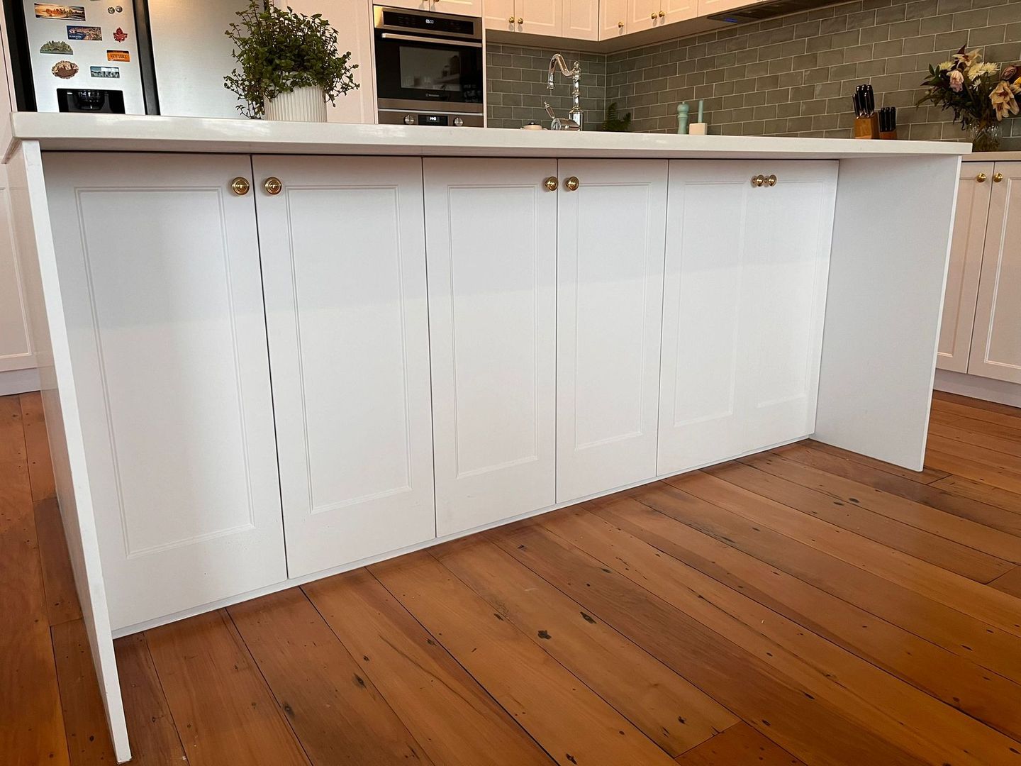 A kitchen with white cabinets and a wooden floor